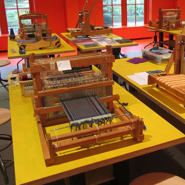 workshop met gele tafels en rode muren en verschillende tafelweefgetouwen