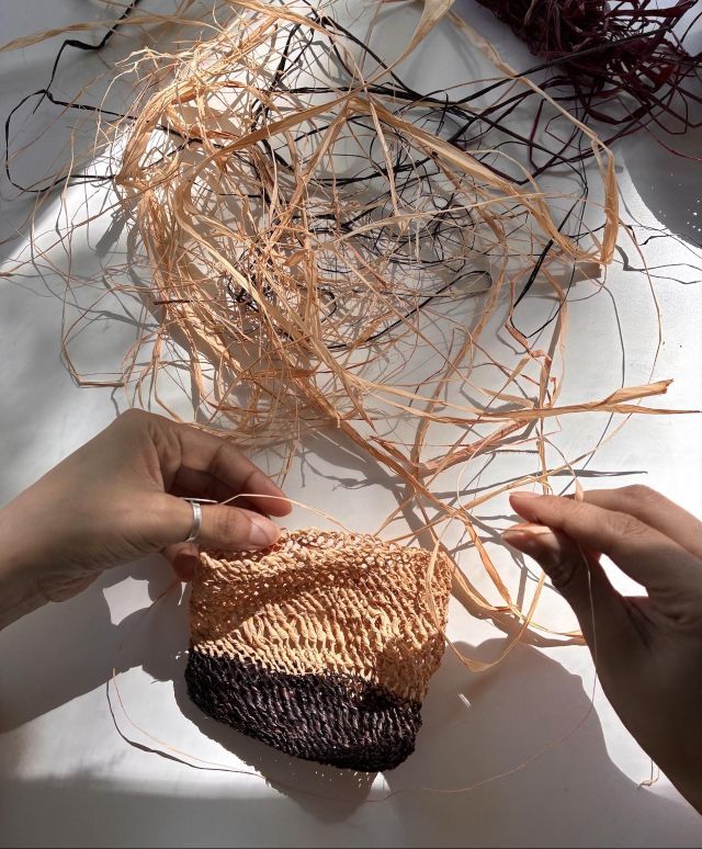 een hand wijst aan hoe de schering door de hevels is geregen