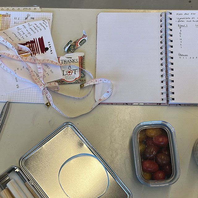 meetlint, aantekenschrift, blikje en bakje pruimen op een werktafel