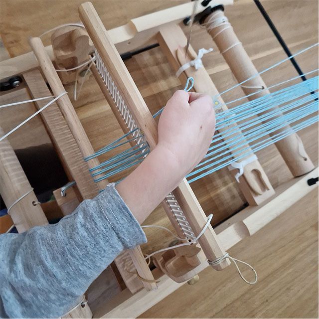 een lichtblauwe schering wordt ingeregen op een rigid heddle loom