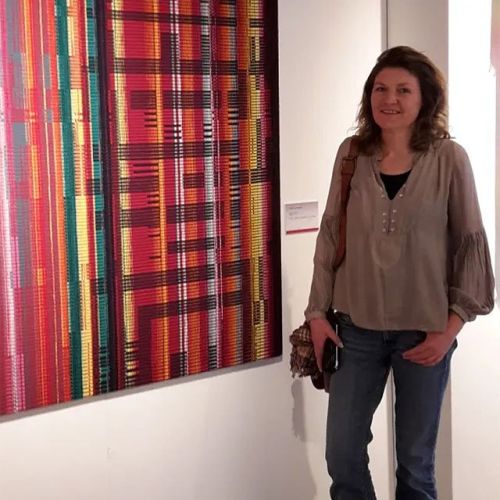 Paulien van Asperen poseert naast een van haar wanddoeken