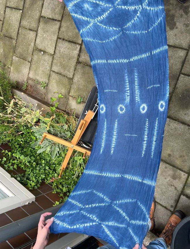 twee personen houden een indigo geverfde sjawl tussen hen in