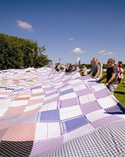 groep mensen houden een gigantisch weefwerk vast op een grasveld