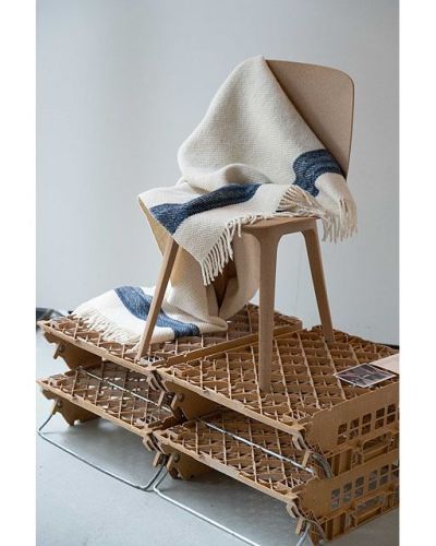 witte wollen deken met blauwe streep gedrapeerd op een stoel op vier kratjes
